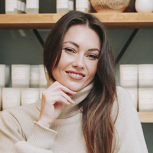 Headshot of Michaela, smiling, wearing a tan turtleneck