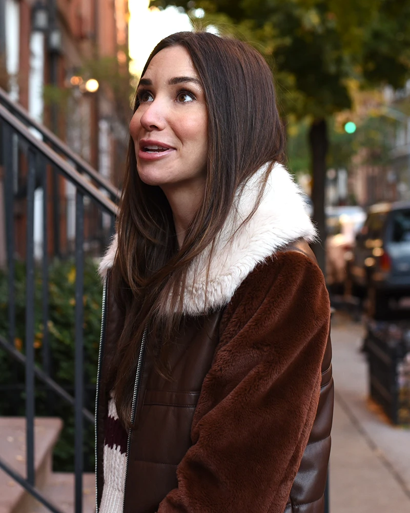 Photo of Blaine in front of a house in West Village, in a brown coat, smiling