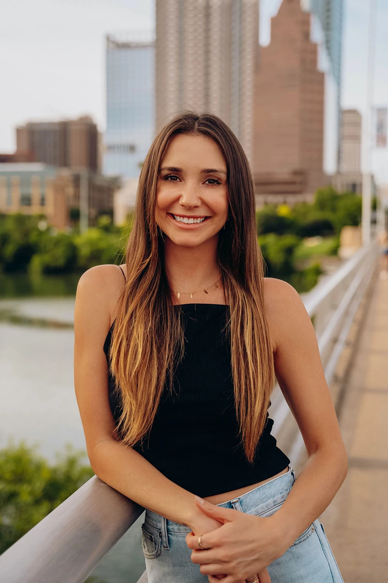 Photo of Blaine on the South Congress bridge, with downtown Austin in the background, smiling